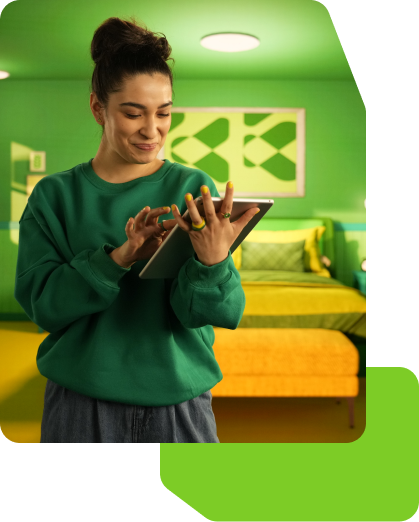 A female looking at her tablet in her bedroom smiling.